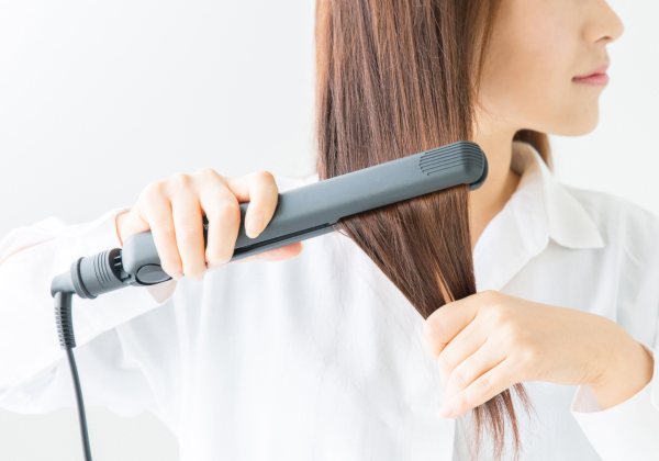 ヘアアイロンを使用している女性